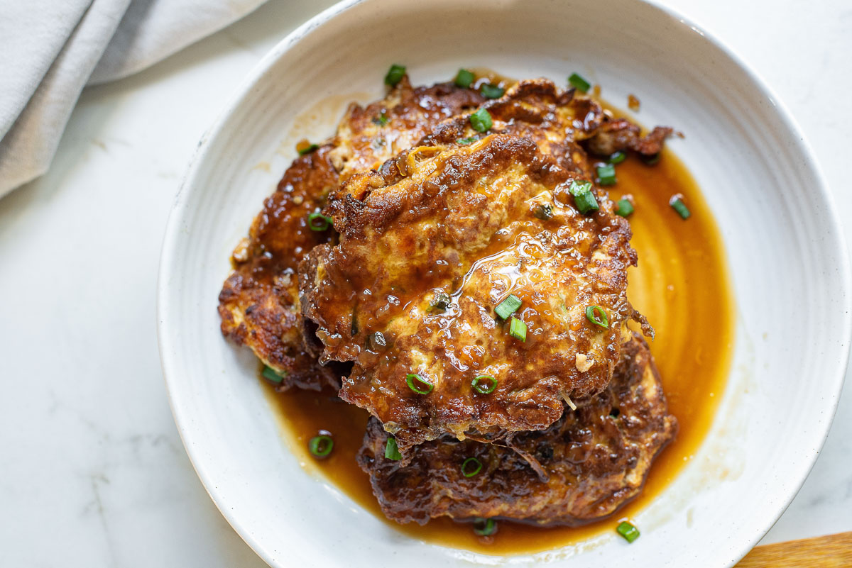 Egg foo young with sauce on a white plate.