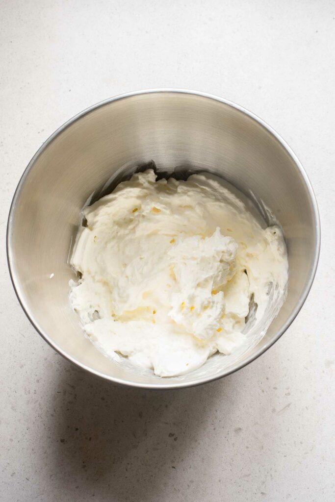 Whipped cream in a metal bowl on a white surface, garnished with Sabayon.