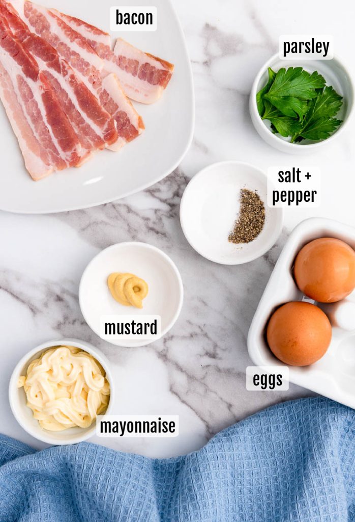 The ingredients for a bacon and egg sandwich on a marble table.
