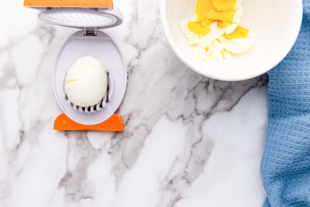 An egg grater and a bowl of eggs on a marble countertop, perfect for making a delicious egg salad.