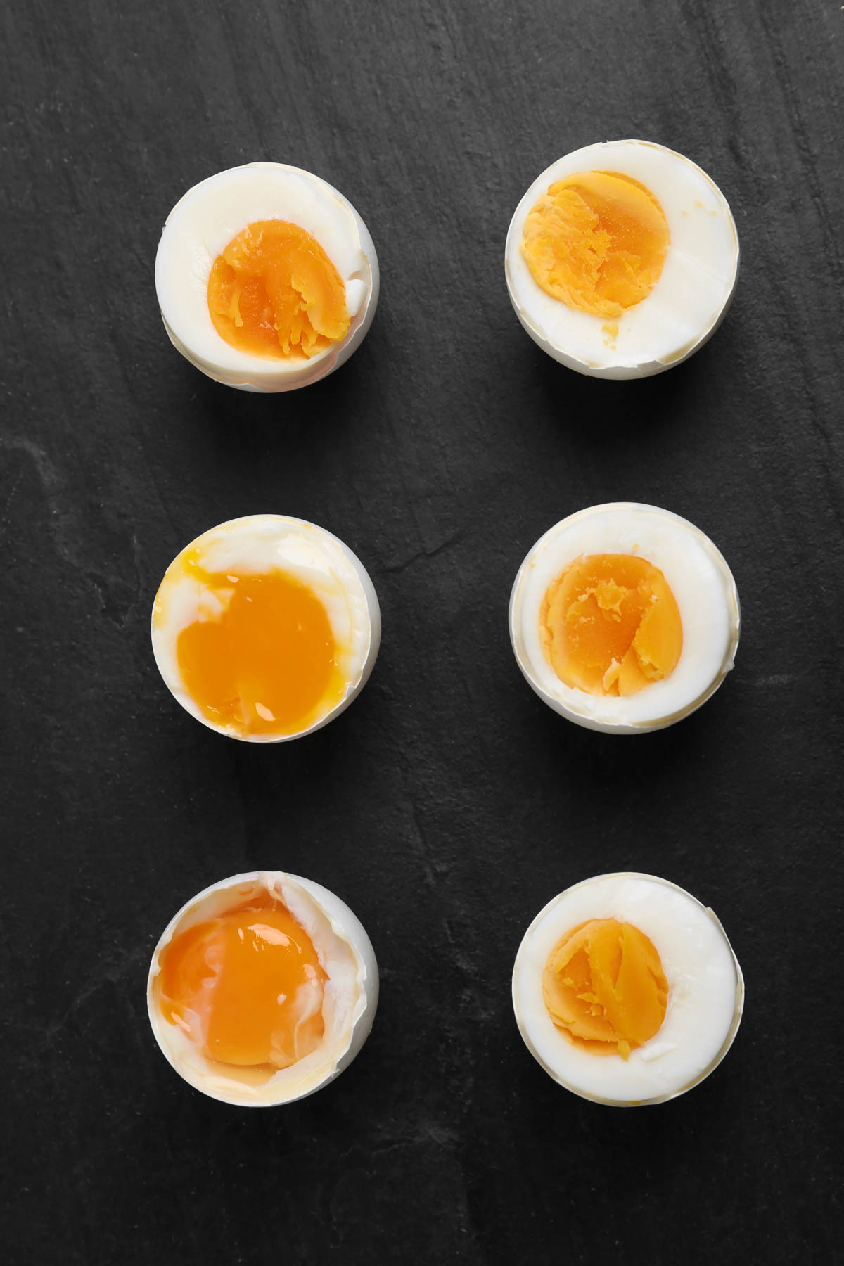 Perfectly boiled eggs at different doneness levels on a black background.