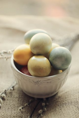 Colored chicken eggs in a white bowl.