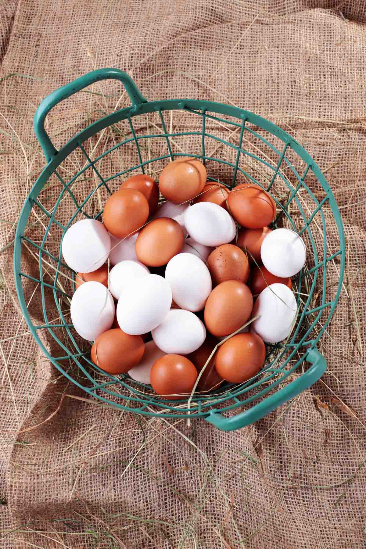 Farm fresh white and brown eggs in a basket on a burlap sack.
