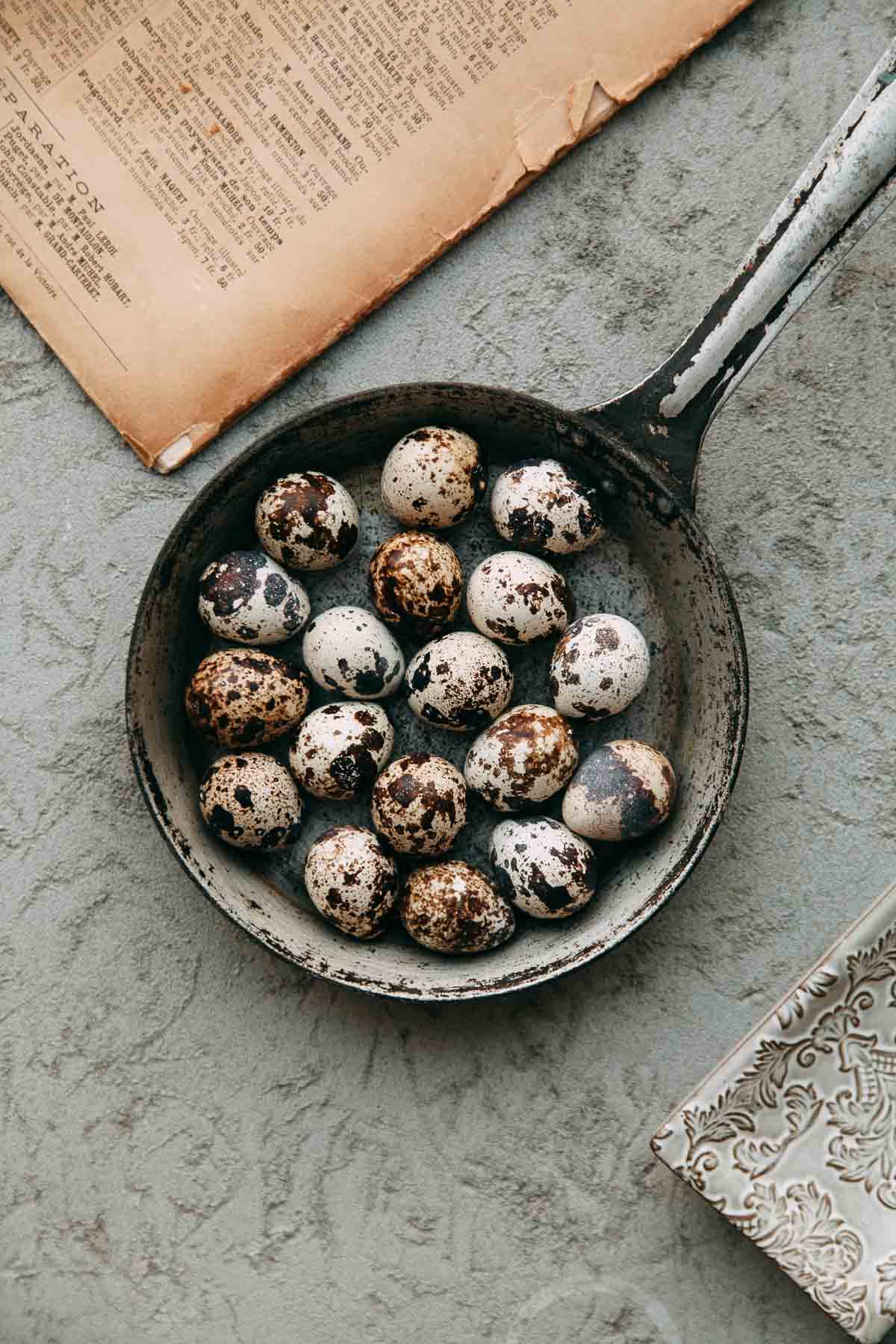 Quail eggs in a frying pan on a table, ready for cooking.