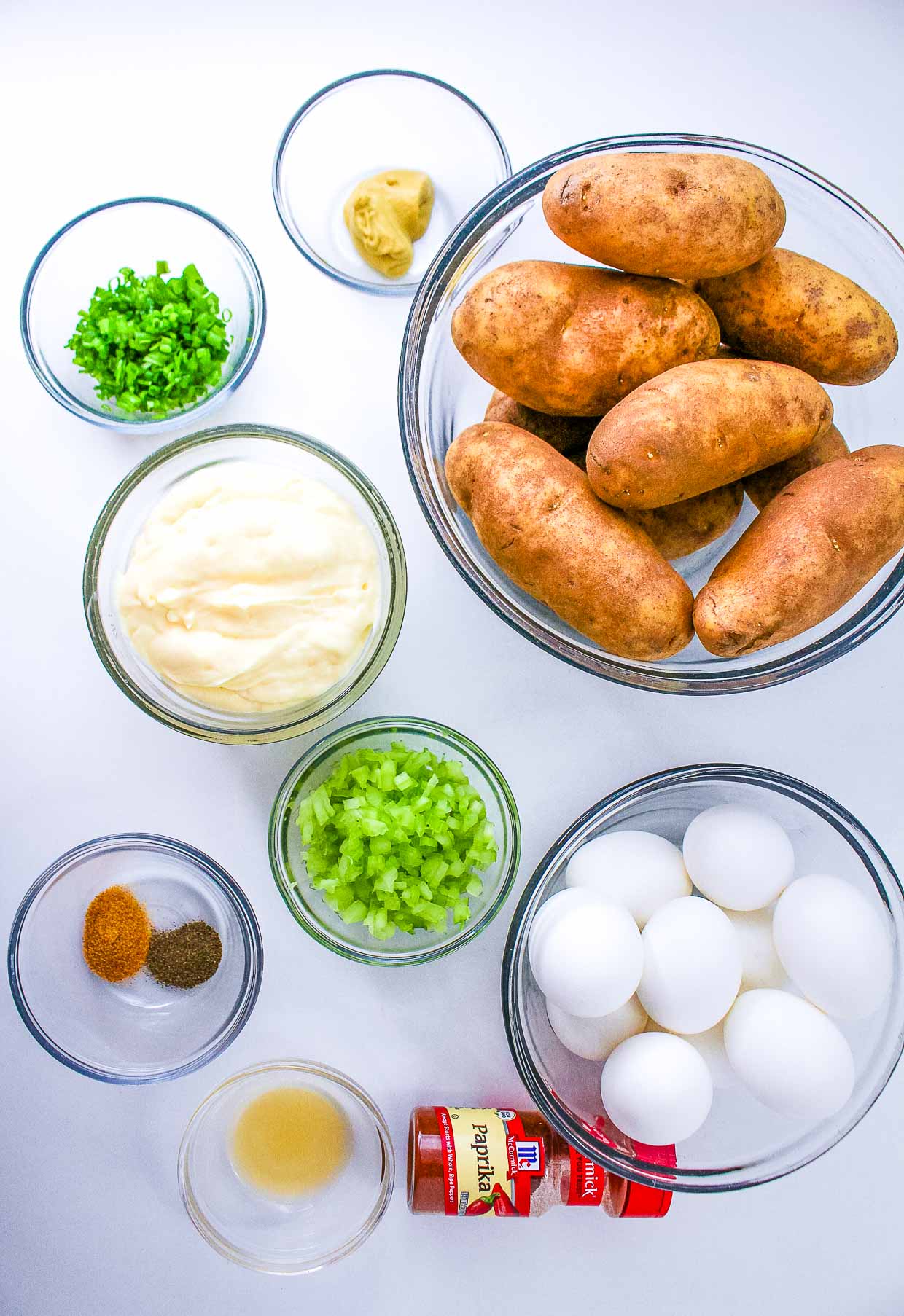 Ingredients for egg potato salad preparation on a white surface.