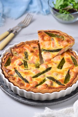 A quiche with asparagus is served on a plate.