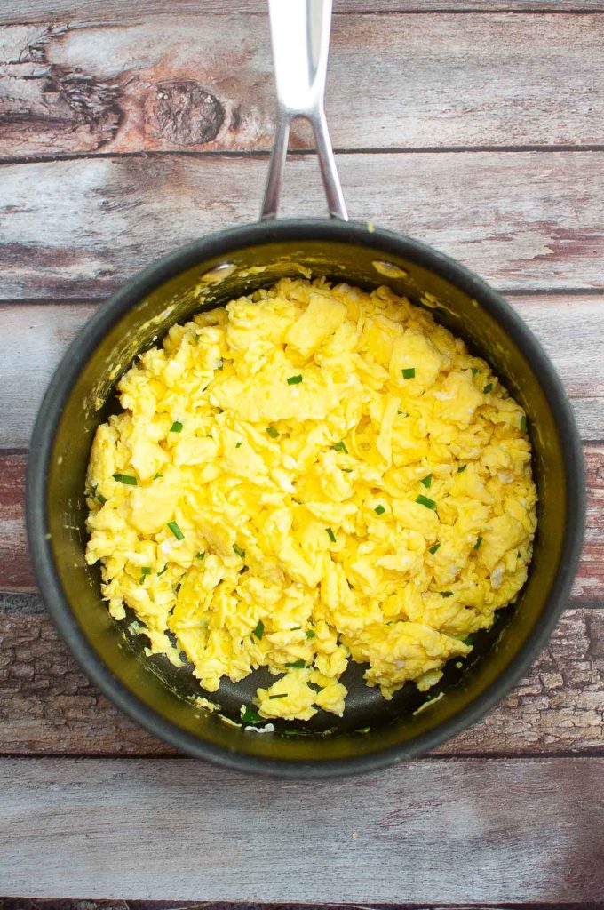 A bowl of scrambled eggs with herbs on a breakfast quesadillas background.