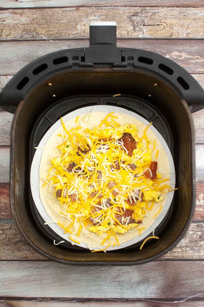 A breakfast quesadilla with cheese and meat fillings being cooked in an air fryer.