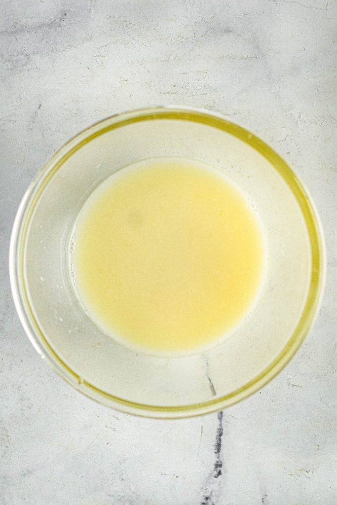 A bowl of Avgolemon soup, a clear Greek soup with lemon, featuring a layer of oil on top.