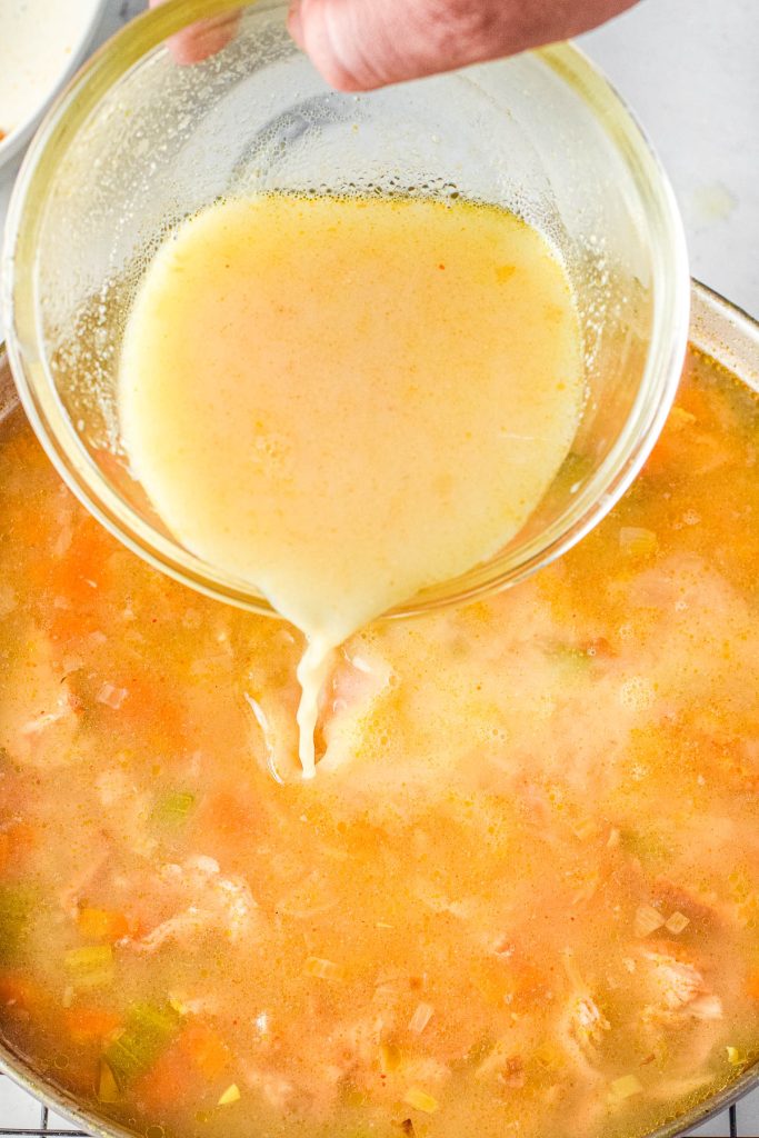 Pouring egg mixture into a simmering pot of Avgolemono Soup.