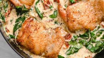 Pan-seared chicken thighs in a creamy spinach sauce served in a skillet.