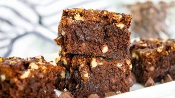 A close-up image of homemade air fried chocolate brownies with nuts and chocolate chips on a white plate.