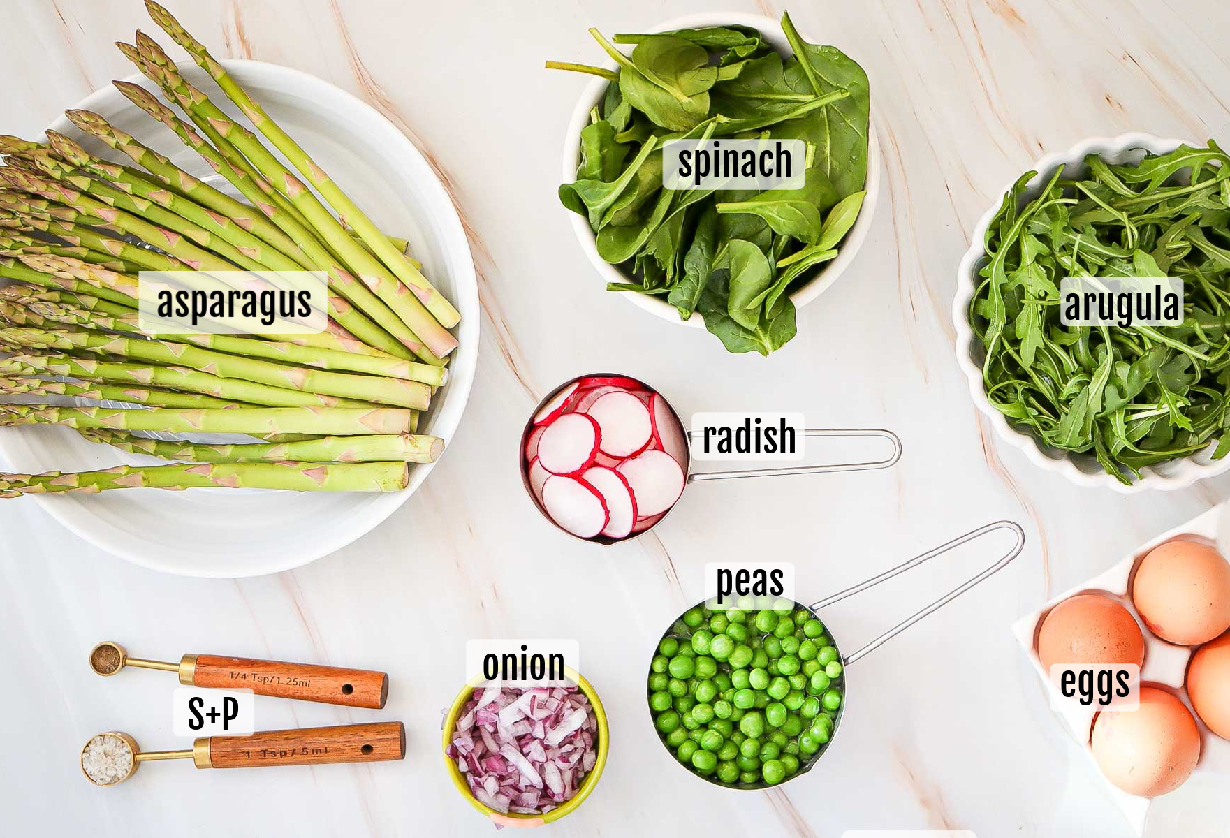 Asparagus, spinach, arugula, radish, onion, peas, and soft-boiled eggs are arranged in bowls and on a counter, each labeled with text—perfect ingredients for a vibrant pea salad. Salt and pepper add the finishing touch.