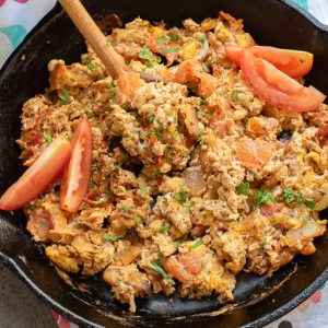 A skillet filled with Menemen—Turkish scrambled eggs, tomatoes, onions, and herbs—garnished with fresh tomato wedges and parsley for a classic Turkish breakfast.