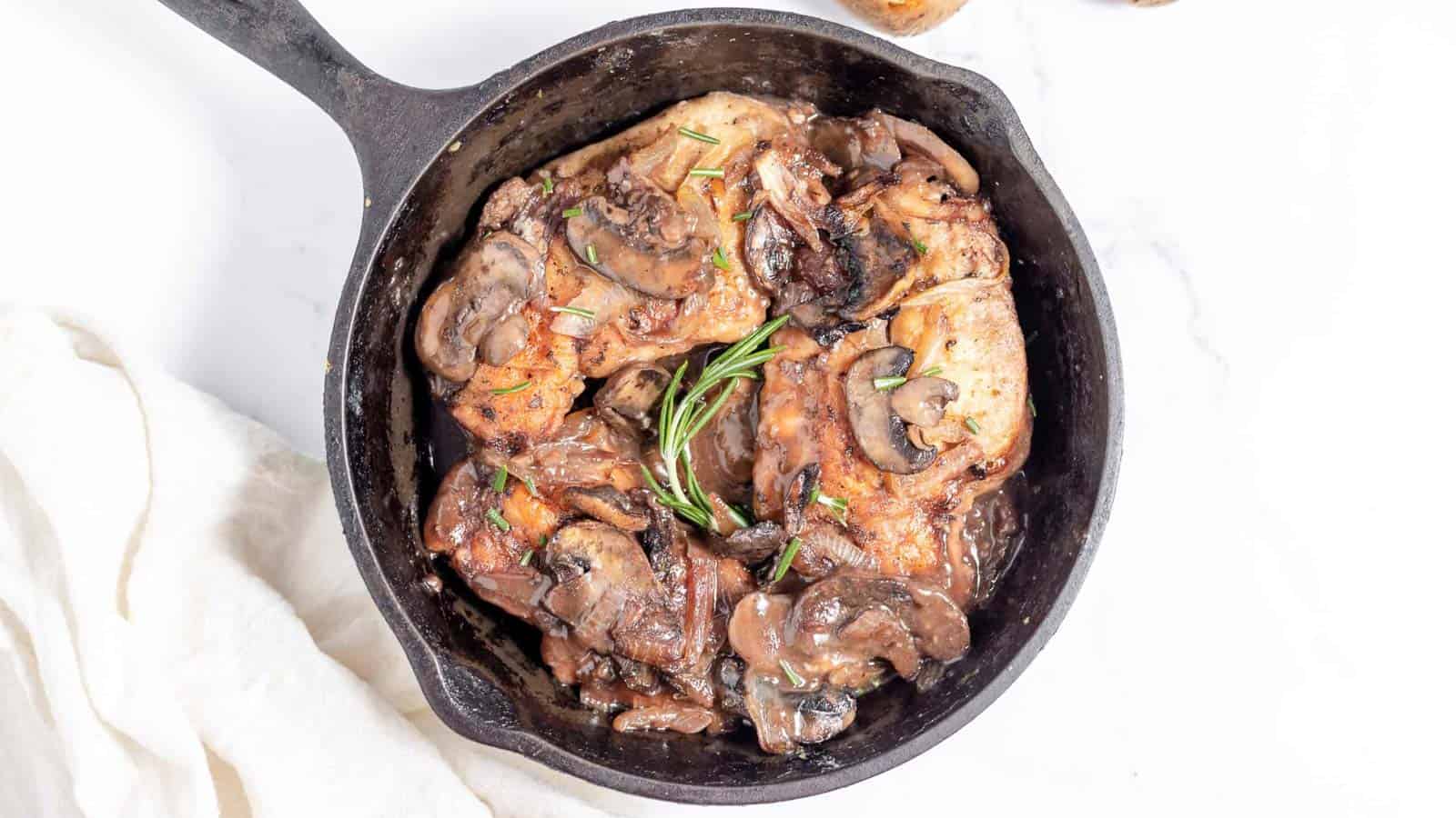 Roasted chicken with mushrooms and potatoes in a cast iron skillet.