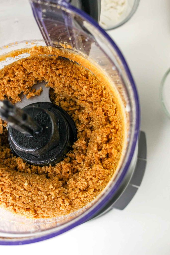 Crushed graham crackers mixed with butter in a food processor create a crumbly base, perfect for Banana Pudding Cheesecake or delicious Cheesecake Squares.
